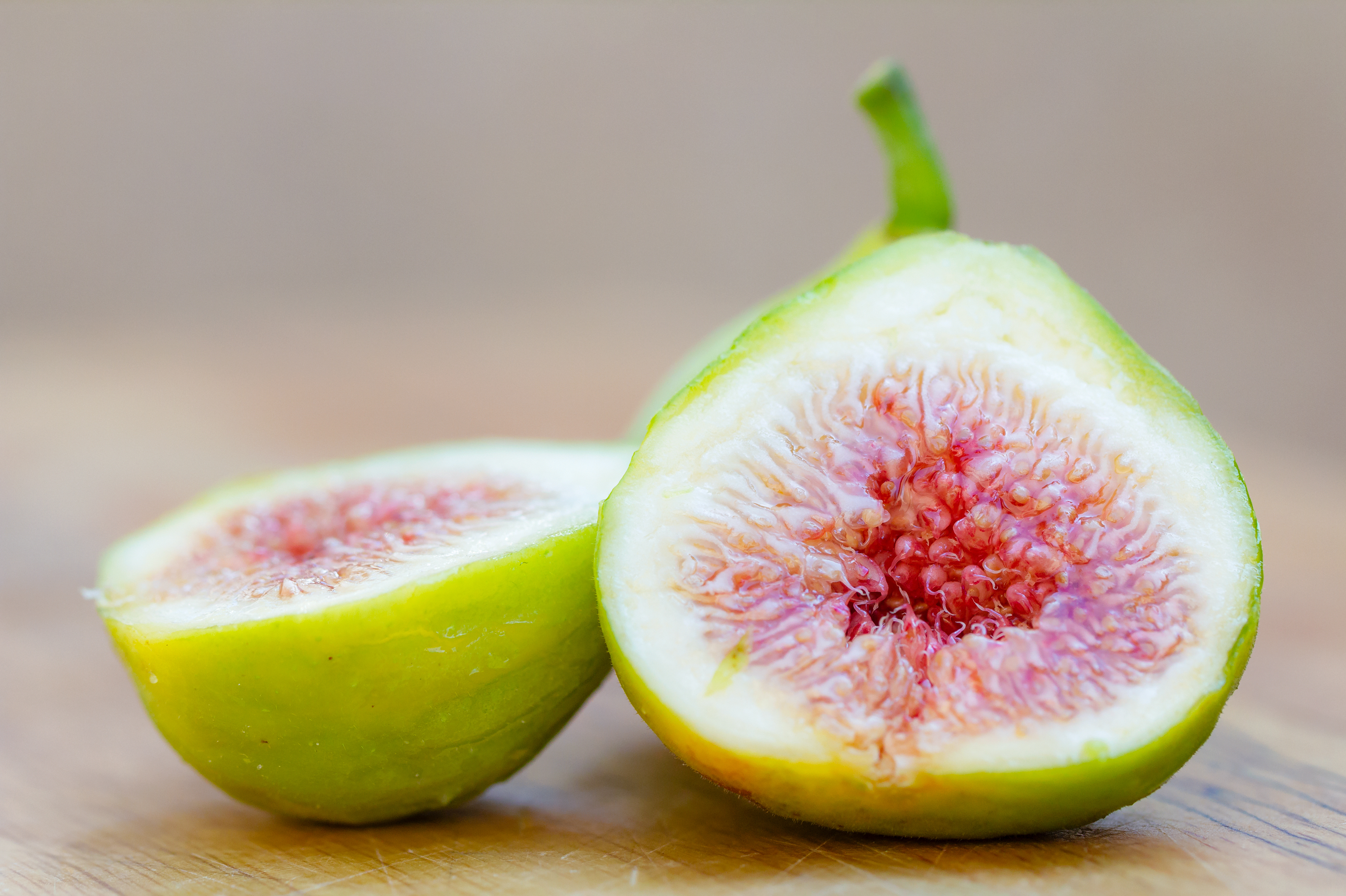 A halved and whole fig isolated on a wooden board