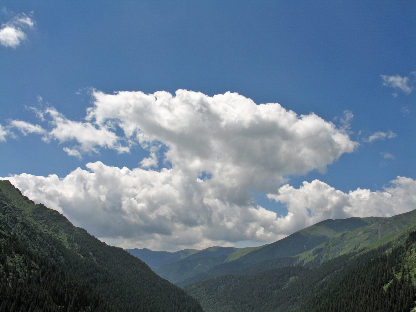 Summer day with puffy clouds over a valley between mountains