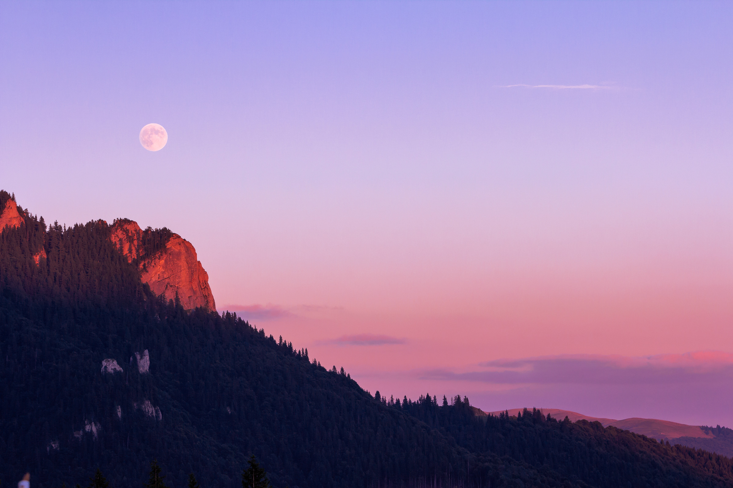 Sunset lit rockface with moon in the background